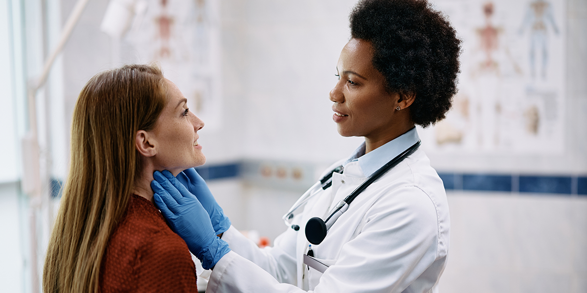 doctor giving female patient a thyroid exam